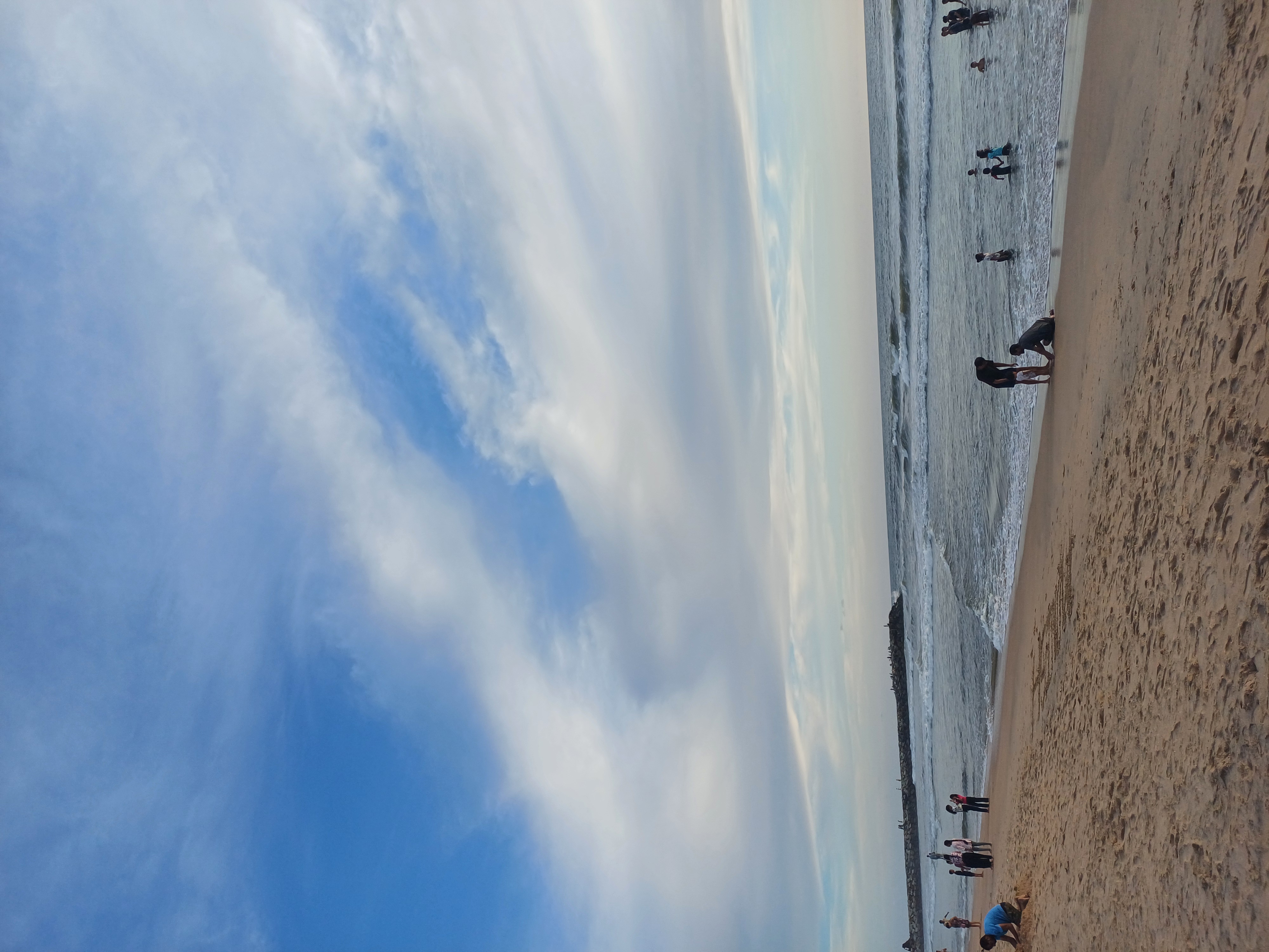 Visitors on the Kannur beach in season, families at the water's edge under a big sky